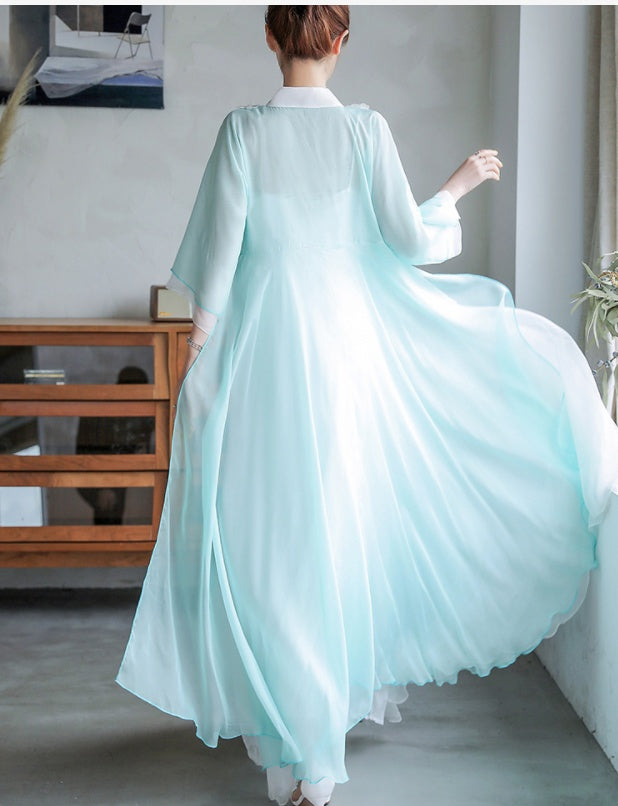 Person wearing a light blue traditional outfit in a room with a wooden cabinet and gray walls.